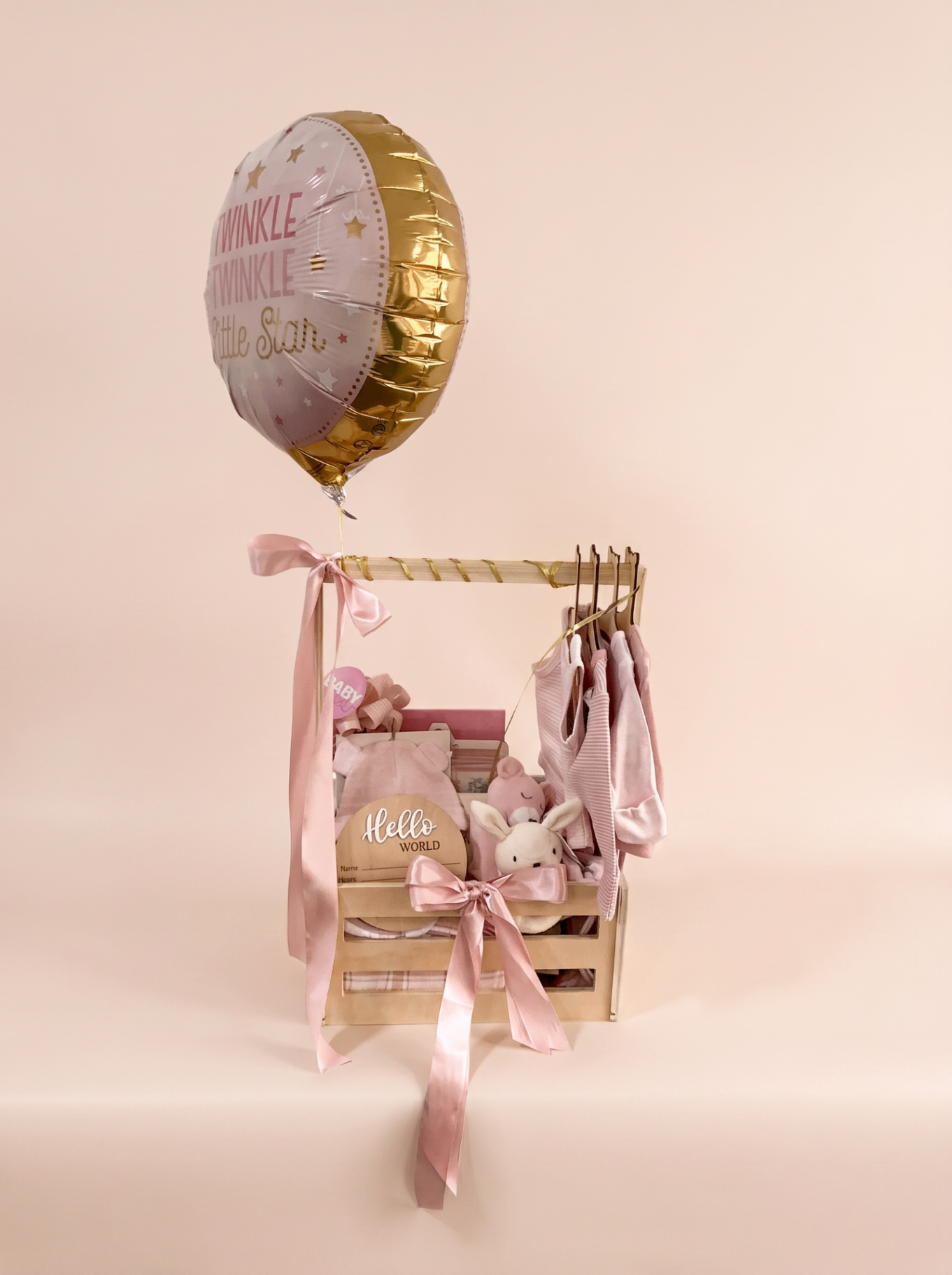 Bespoke pink baby shower crate with hot air balloon, satin ribbons, tiny rail of newborn pieces and keepsakes